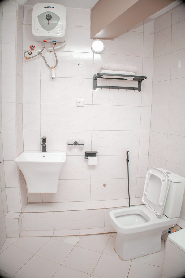 Un baño con inodoro, lavamanos y perchero para toallas.
