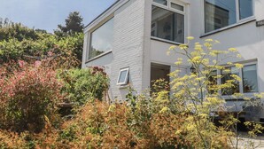 Una casa moderna de dos pisos con fachada blanca, ventanas grandes y una puerta visible.