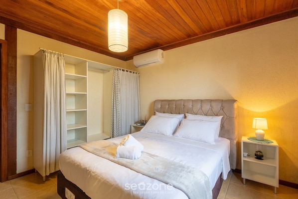 Un dormitorio con cama, mesita de noche, lámpara, aire acondicionado y armario.