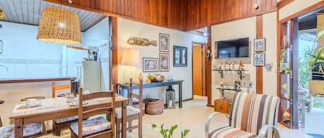 A cozy living area with wooden furniture, a dining table, and a TV mounted on the wall.