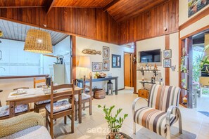 Un espacio de sala acogedor con muebles de madera, una mesa de comedor y un televisor montado en la pared.