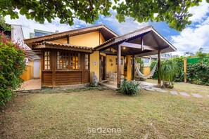 Una casa con un porche cubierto, una hamaca y un pequeño jardín.