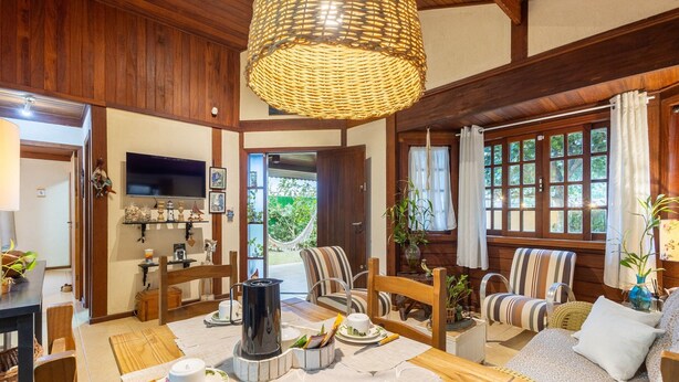 A cozy living room with a fireplace, striped chairs, and a television. - Charming House With BBQ by the sea Mon0099 (Barra Velha)