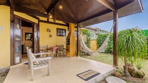A covered outdoor seating area with wooden chairs and a table, a hammock, and a doormat with a message. - Charming House With BBQ by the sea Mon0099 (Barra Velha)