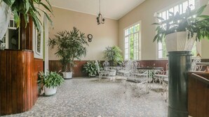 Un vaste espace intérieur doté d’un sol carrelé, de plantes en pot et de meubles en métal.