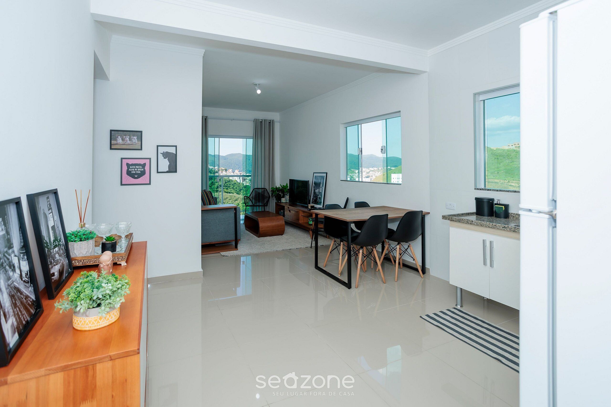 A modern kitchen with a dining area, large windows, and a view of the outdoors.