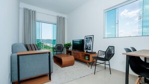 A modern living room with a sofa, a coffee table, a TV, and a dining area with chairs. - Apt 8min From Center Pocos de Caldas-mg Mbi022 (Poços de Caldas)