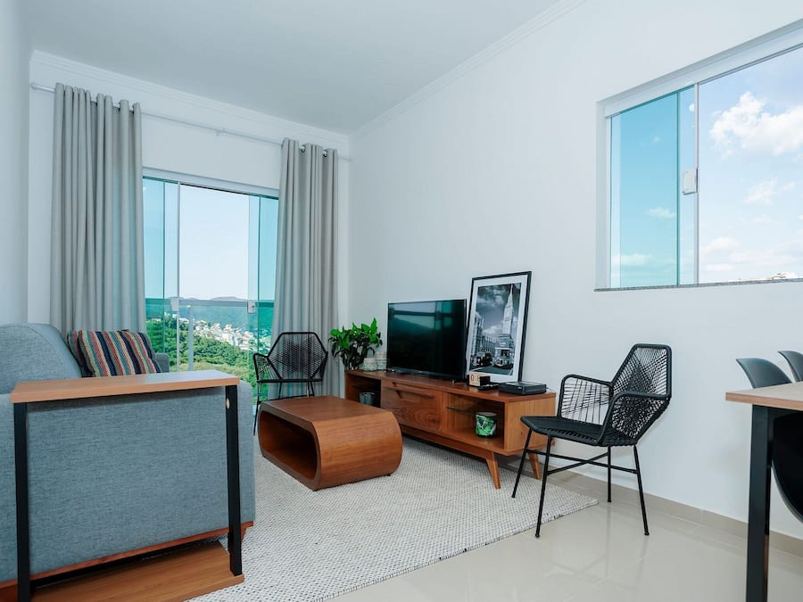 A modern living room with a sofa, a coffee table, a TV, and a dining area with chairs.