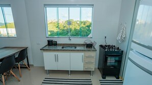 A modern kitchen with a window view, a gas stove, and a dining area with chairs. - Apt 8min From Center Pocos de Caldas-mg Mbi022 (Poços de Caldas)