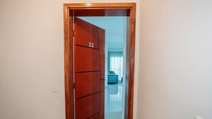 A wooden door with the number 22, leading to a room with a blue sofa and a window with curtains. - Apt 8min From Center Pocos de Caldas-mg Mbi022 (Poços de Caldas)