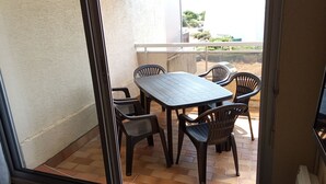 Un balcon avec une table et des chaises, une vue sur l’extérieur et un cadre de porte.