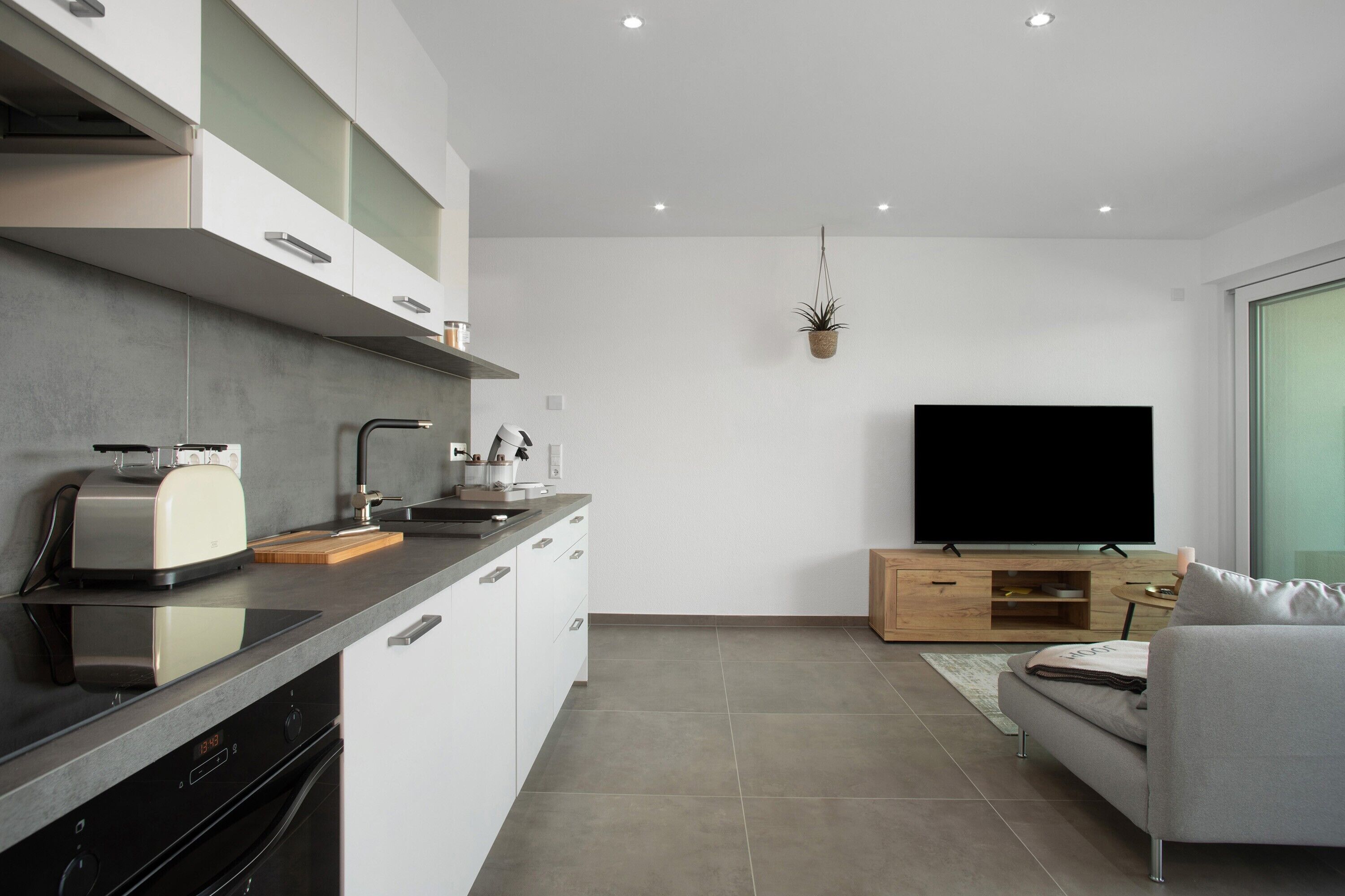 A modern kitchen with a built-in oven, a toaster, and a sink.