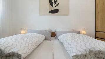 A double room with two beds, each with a patterned bedspread, a wall-mounted artwork, and bedside lamps.