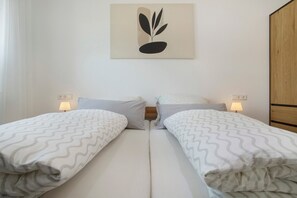 Une chambre double avec deux lits, chacun agrémenté d’une couvre-lit à motifs, d’une œuvre d’art accrochée au mur et de lampes de chevet.