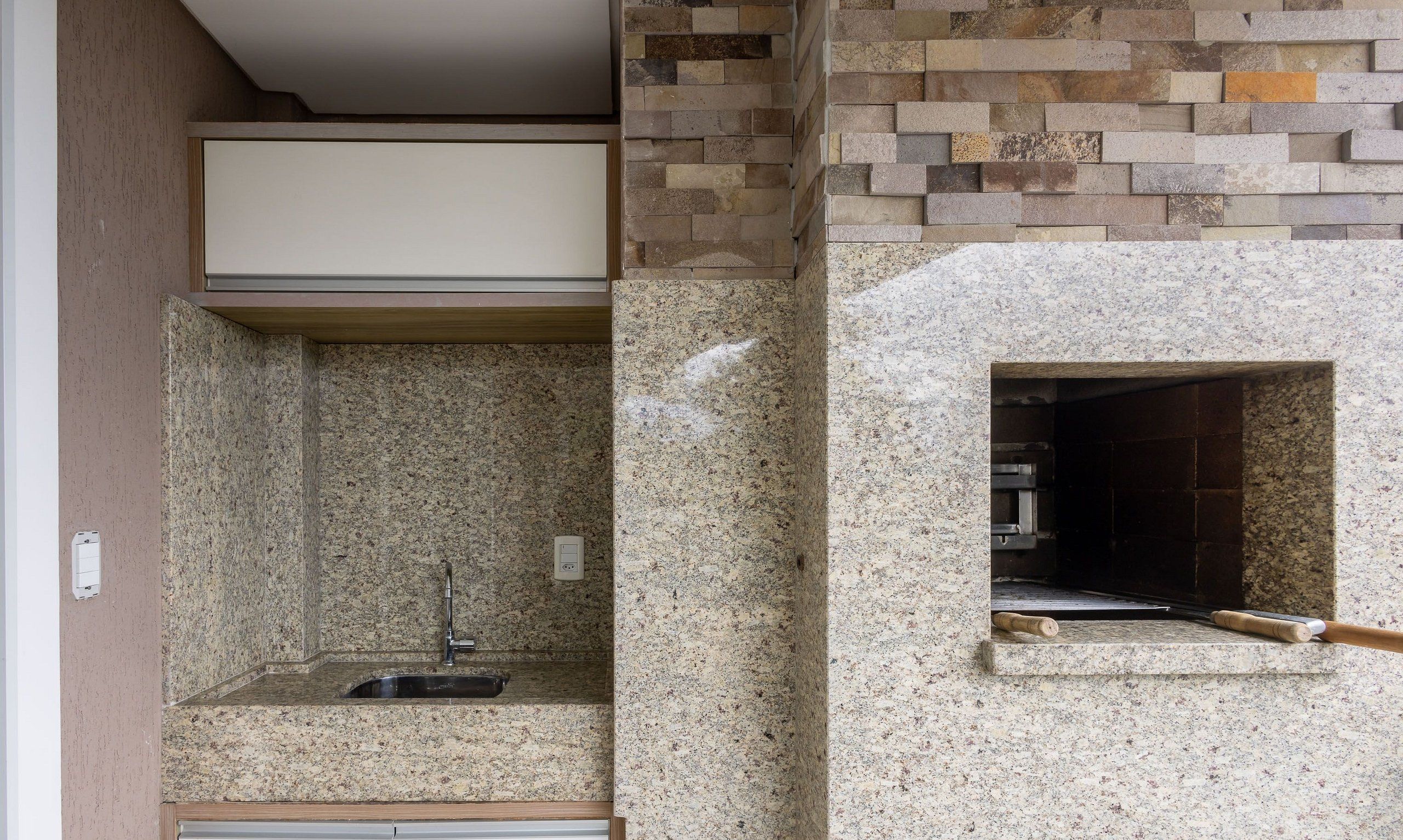 Cozinha com bancadas de granito, pia embutida e backsplash de pedra.