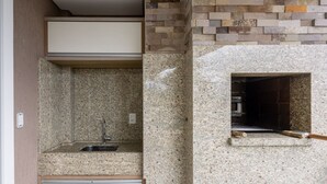 A kitchen with granite countertops, a built-in sink, and a stone backsplash. - Sea View Apartment w Barbecue in Bombinhas Lga0201 (Bombinhas)
