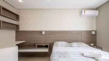Un dormitorio moderno con cabecera de madera, mesita de noche integrada, cama con edredón acolchado y unidad de aire acondicionado en la pared.