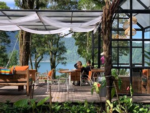 Un espacio al aire libre con mobiliario de madera y vista a un lago.