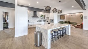 Een moderne keuken met een marmeren eiland, hangende lampen en een strak, minimalistisch design.
