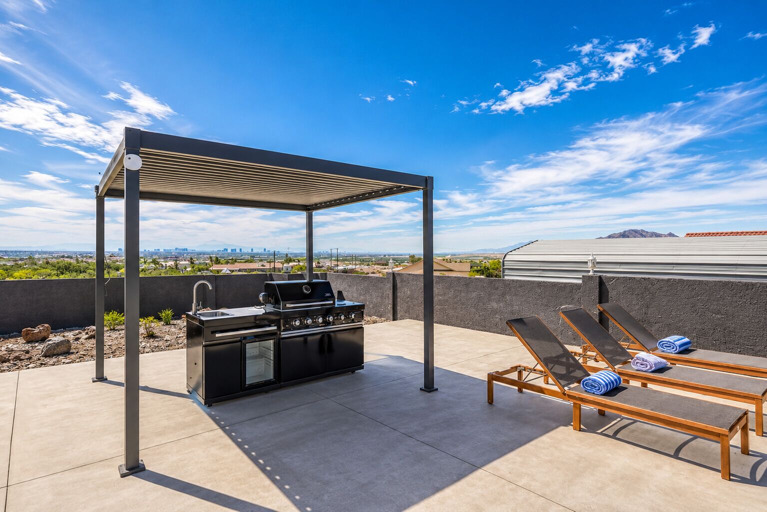 Patio esterno con barbecue, poltrone relax e pergola.