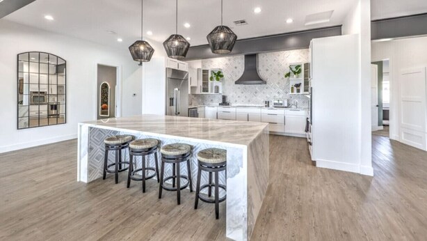 Een ruime keuken met een groot schiereiland, barstoelen, hanglampen en een modern design.