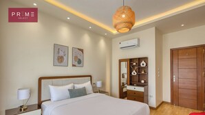 A hotel room with a bed, bedside tables, a dresser, a mirror, and a wardrobe.