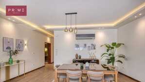 A modern dining area with a wooden table, four chairs, and a large potted plant.
