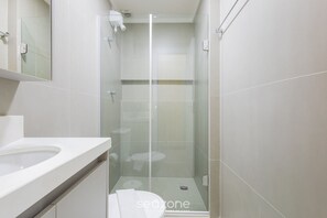 A modern bathroom with a glass-enclosed shower, a white sink, and a mirror above the sink. - Fully Equipped Accommodations in the Heart of Brasilia LEC (Sudoeste e Octogonal)