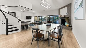 A modern kitchen with a large dining table, a staircase, and a fireplace. - 25%Off Sep 24-27 Waterfront Great 4 Families -Dock (Oxnard)