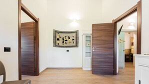 A hallway with wooden doors, a light fixture, a tapestry, and a white cabinet.