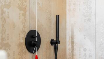A bathroom with a shower head mounted on a wall with decorative tiles.