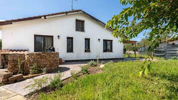 Un edificio bianco con una parete in pietra, finestre e un giardino.
