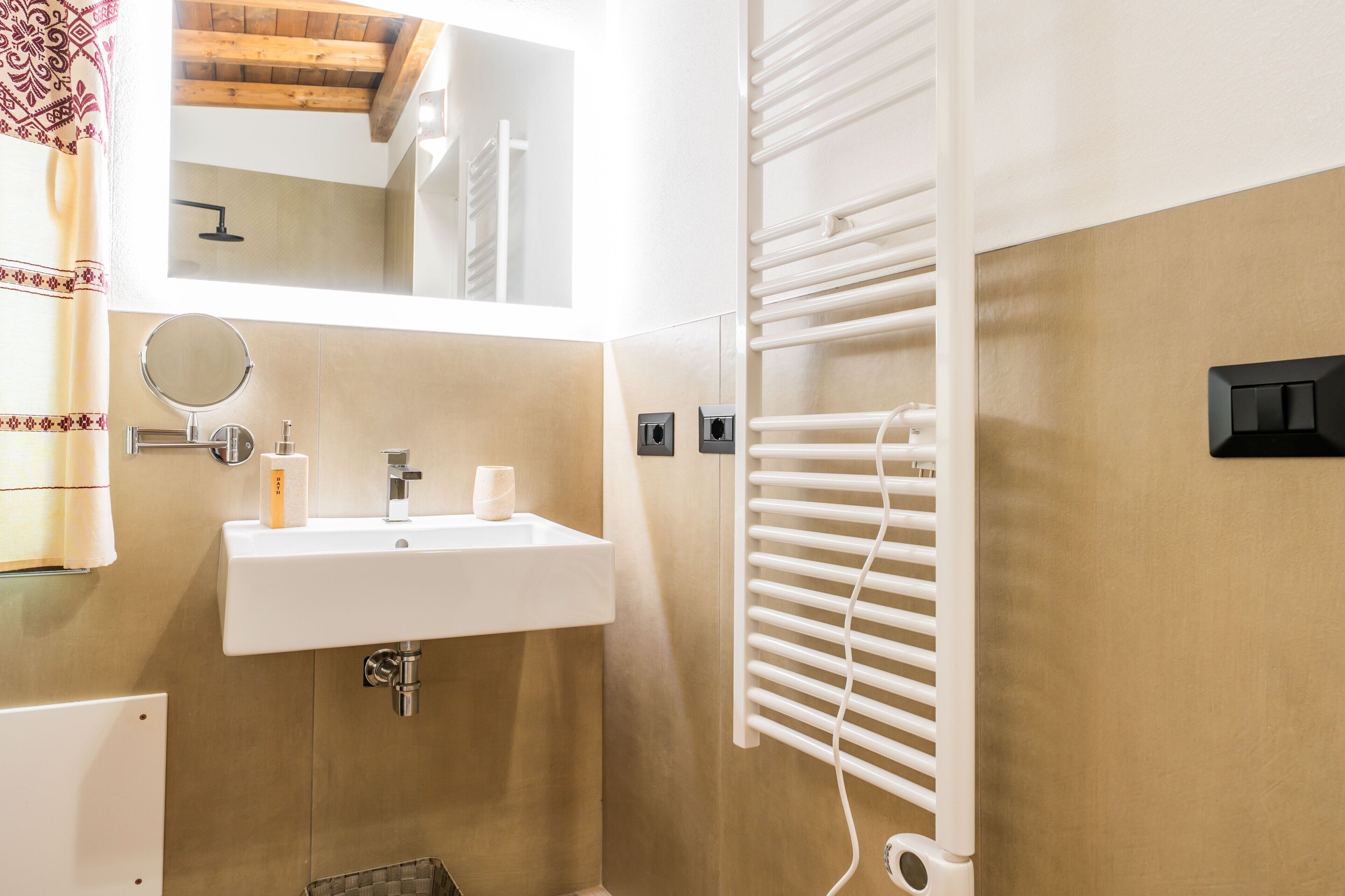 Une salle de bain équipée d’un lavabo, d’un miroir, d’un porte-serviettes et d’une serviette accrochée au mur.