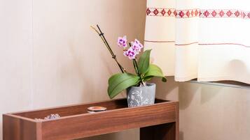 A wooden console table with a potted orchid and a candle.