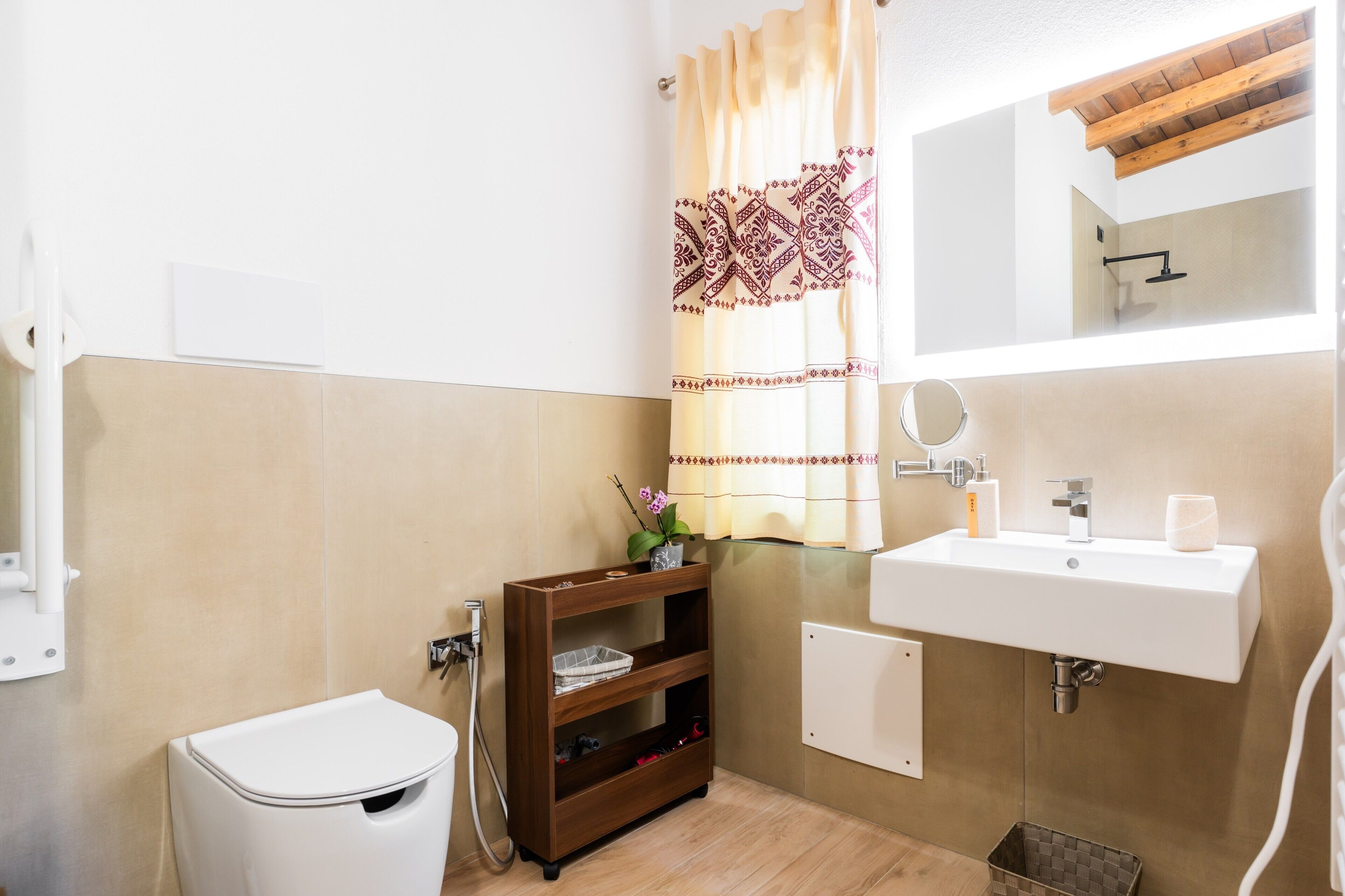 A bathroom with a toilet, a wooden shelf with toiletries, a sink, and a mirror.