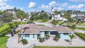 A single-story house with a flat roof, surrounded by a well-maintained lawn and palm trees.