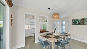 A modern kitchen with white cabinets, a microwave, and a hanging light fixture.
