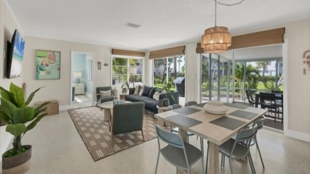 A spacious living area with a dining table, comfortable seating, and large windows offering a view of the outdoors.