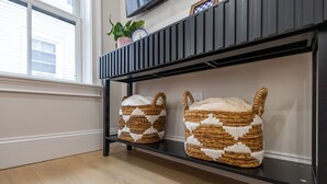 Ein Zimmer mit einem schwarzen Metallregal, auf dem zwei gewebte Körbe mit weißen und braunen Mustern stehen.