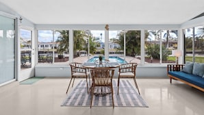 A sunroom with a pool view, wicker furniture, and a blue sofa. - River House Retreat — Canal Views and Poolside Bliss! (Bradenton)