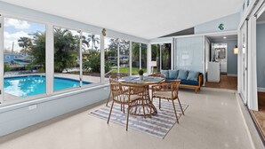 A spacious living area with a pool view, a dining table with chairs, and a sofa. - River House Retreat — Canal Views and Poolside Bliss! (Bradenton)