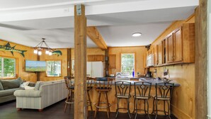 Un intérieur en bois comprenant un coin cuisine, des tabourets de bar et un canapé.