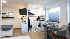 Un espacio habitable compacto con kitchenette, comedor y una pequeña zona de estar.