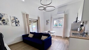 Una sala moderna con un sofá azul, una mesa de comedor y una zona de cocina.