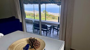 Una habitación con una mesa, un cuenco de granos de café y vista al océano.