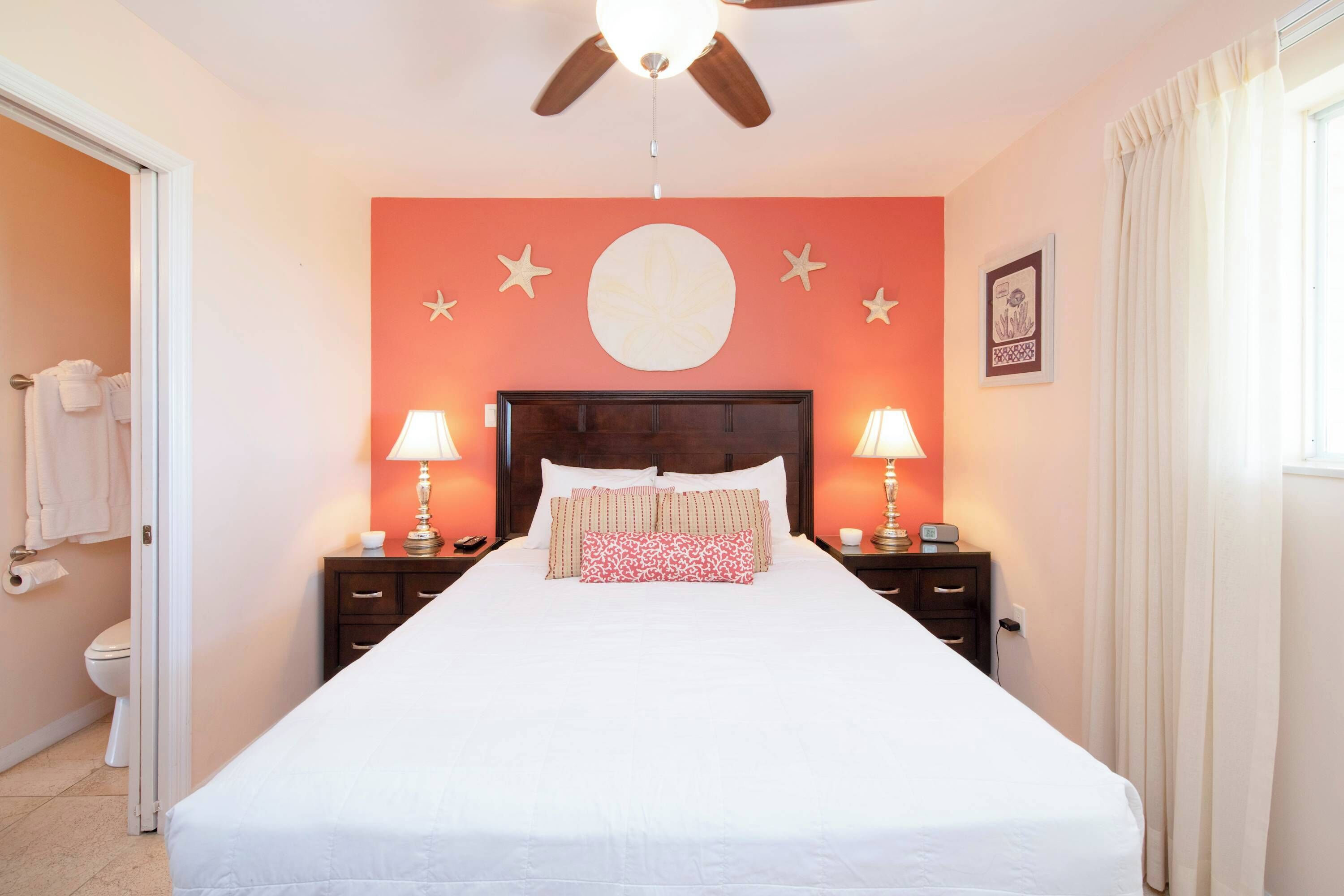 Une chambre à coucher avec un lit, des tables de chevet, des lampes, un ventilateur de plafond et un mur décoré d’étoiles.