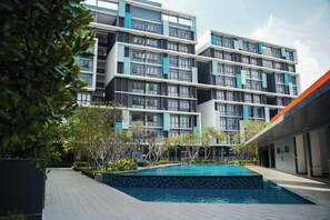 A modern building with multiple balconies and a swimming pool in the foreground. - KLIA Airport Homestay 12 (Sepang)