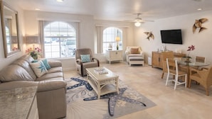 A spacious living room with a sofa, armchairs, a coffee table, and a dining area with chairs and a table. - Block to Beach - Pool - Up to 6 - Families (South Padre Island)