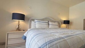 A bedroom with a bed, two bedside tables, and two wall-mounted lamps. - Block to Beach - Pool - Up to 6 - Families (South Padre Island)