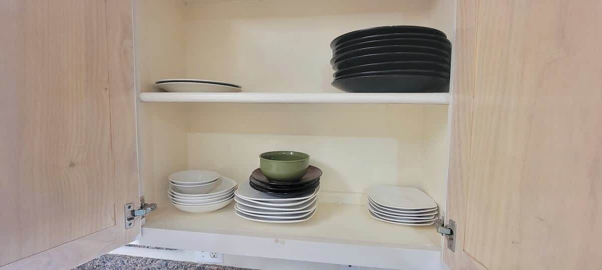 A cabinet with shelves holding plates and bowls.